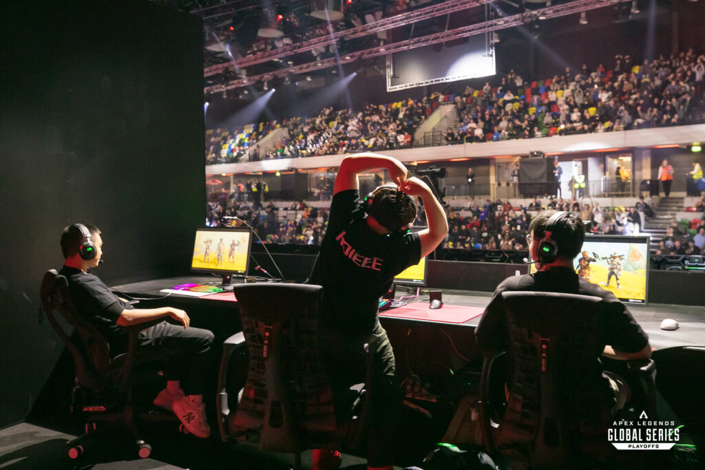 An Apex Legends esports professional makes a heart gesture towards a packed crowd.